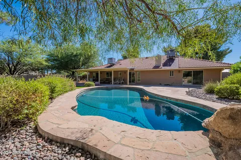 a view of house with swimming pool and yard