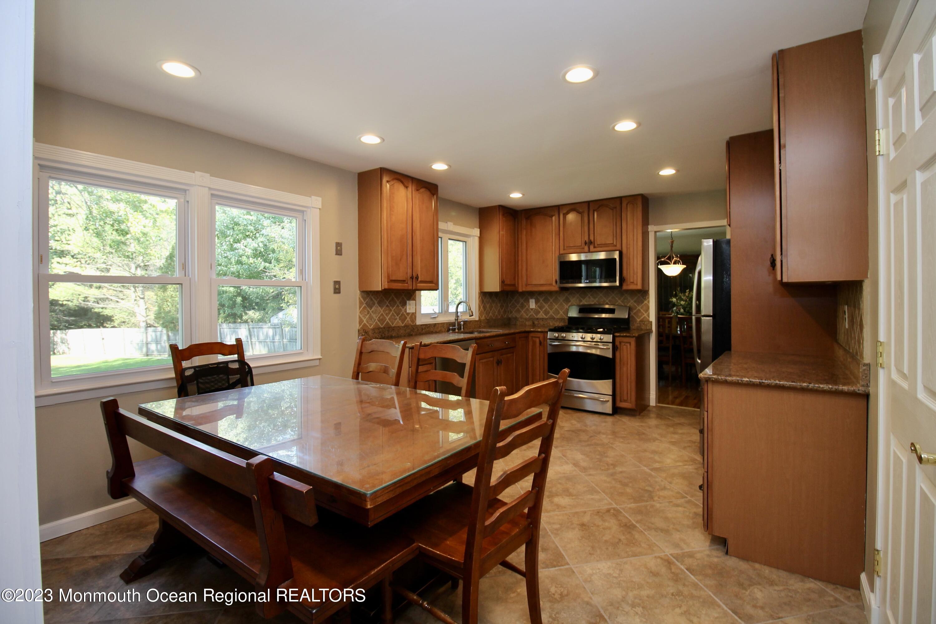 259 Kings Mountain Road Freehold, NJ 07728 - Photo 16 of 61 a kitchen with stainless steel appliances granite countertop a refrigerator a sink dishwasher a stove and a dining table with wooden floor