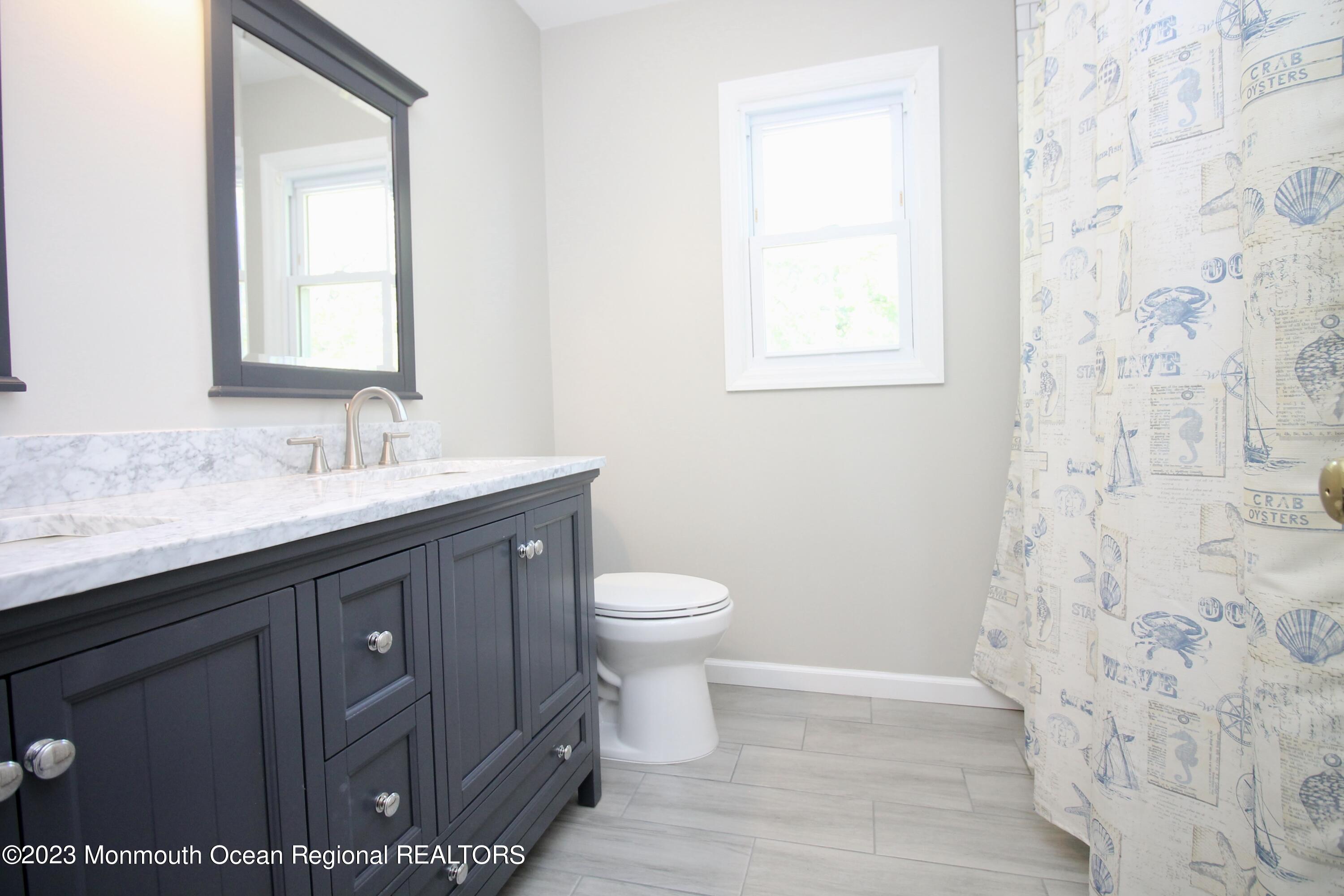 259 Kings Mountain Road Freehold, NJ 07728 - Photo 42 of 61 a bathroom with a granite countertop toilet a sink a mirror and a shower