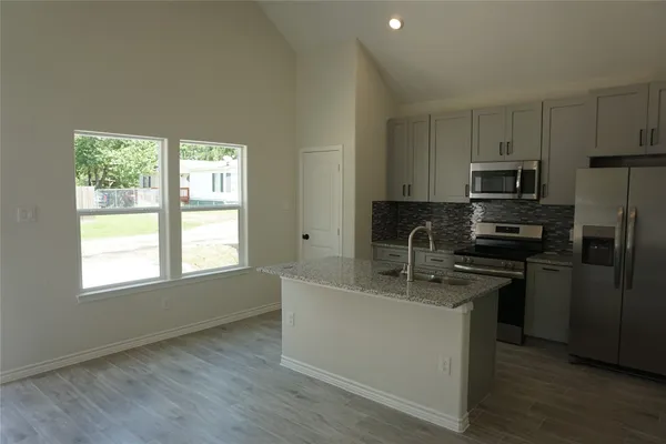 a kitchen with kitchen island granite countertop a sink cabinets and stainless steel appliances