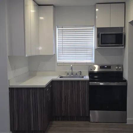 a view of an empty room with wooden floor and a sink