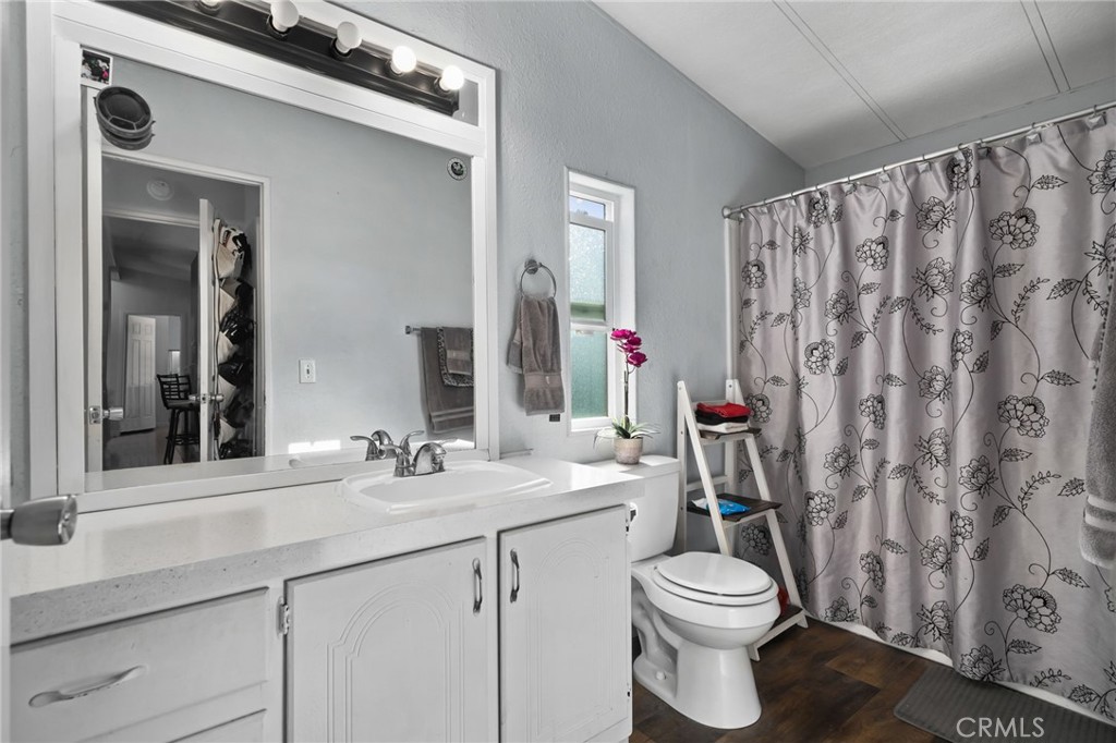 80 East Dawes, Unit 52 Perris, CA 92571 - Photo 14 of 21 a bathroom with a sink a toilet and shower curtain