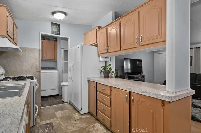 a kitchen with stainless steel appliances granite countertop a refrigerator a stove and a sink