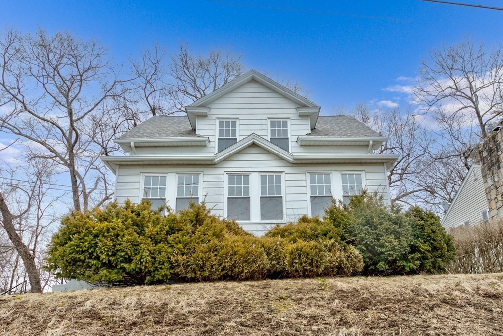 a view of a white house next to a yard with large trees