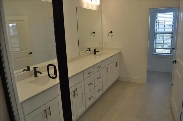 a bathroom with a double vanity sink a mirror and a bathtub