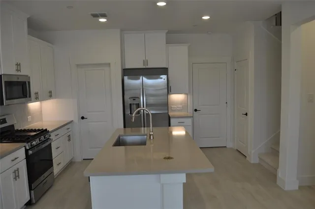 a kitchen with stainless steel appliances granite countertop a sink a stove and a refrigerator