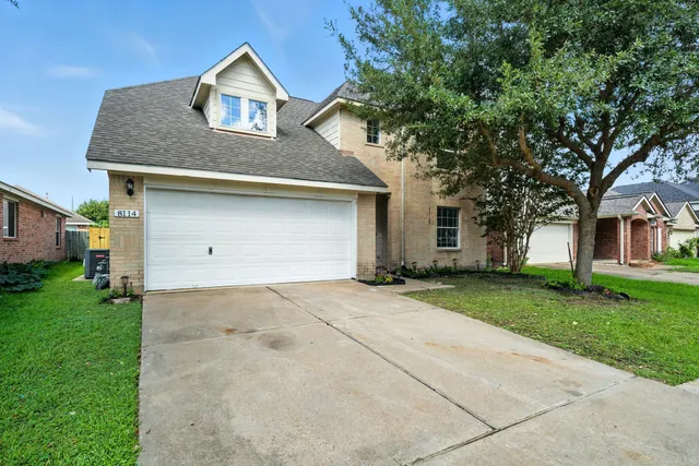 front view of house with a yard and trees all around