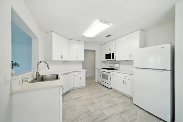 a kitchen with white cabinets and white appliances