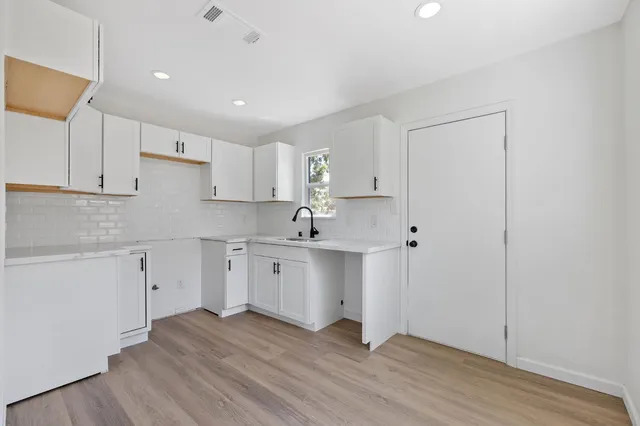 a kitchen with wooden floors and white cabinets