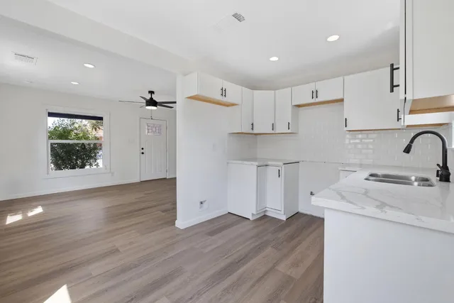 a kitchen with a sink a stove a refrigerator and white cabinets with wooden floor