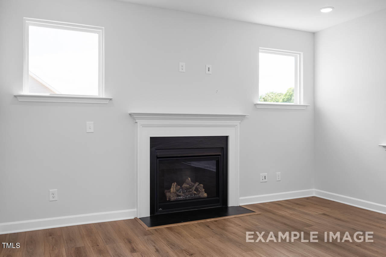 271 Crop Road Angier, NC 27501 - Photo 14 of 28 an empty room with a fireplace and wooden floor