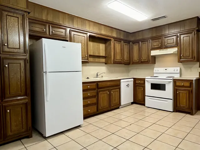 a kitchen with a refrigerator sink and wooden cabinets