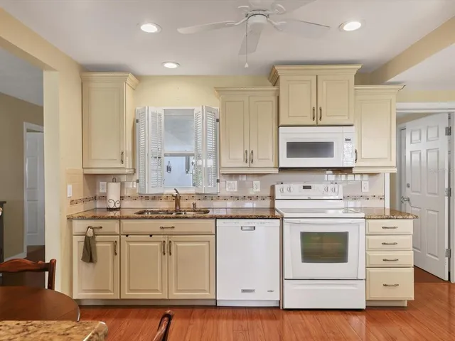 a kitchen with white cabinets white stainless steel appliances and sink