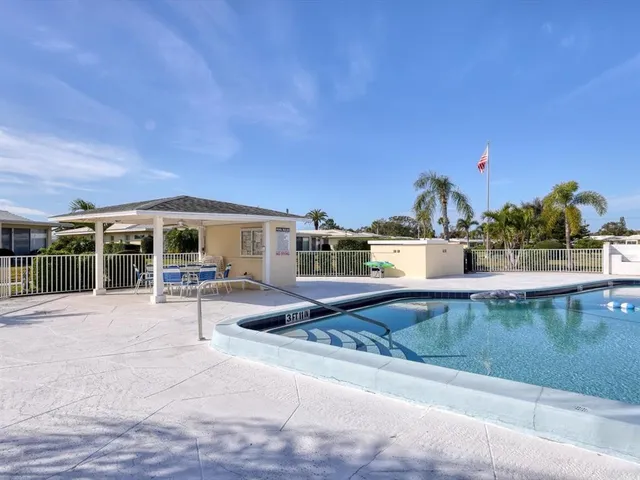 a view of swimming pool with a table and palm trees