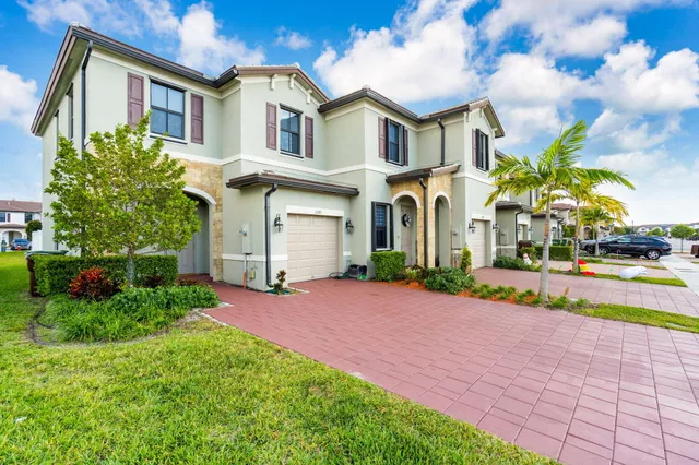 a front view of a house with a yard and potted plants