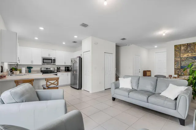 a living room with furniture kitchen area and a refrigerator