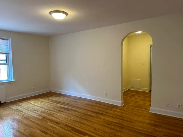 an empty room with wooden floor and window