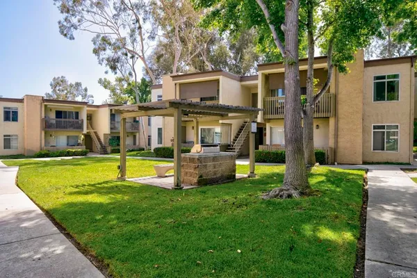 a view of a house with a big yard with plants and large trees