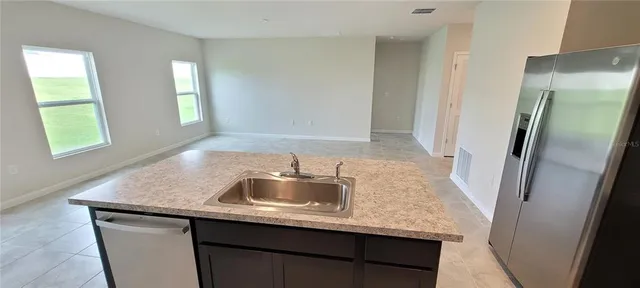 a kitchen with kitchen island granite countertop a sink a refrigerator and window