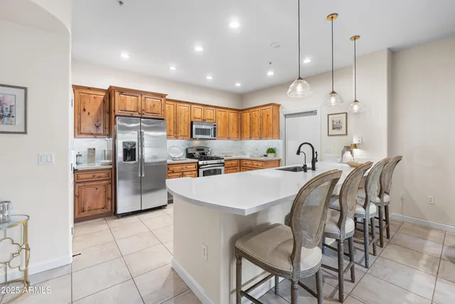 a kitchen with stainless steel appliances kitchen island granite countertop a stove a refrigerator a oven a sink with a dining table and chairs