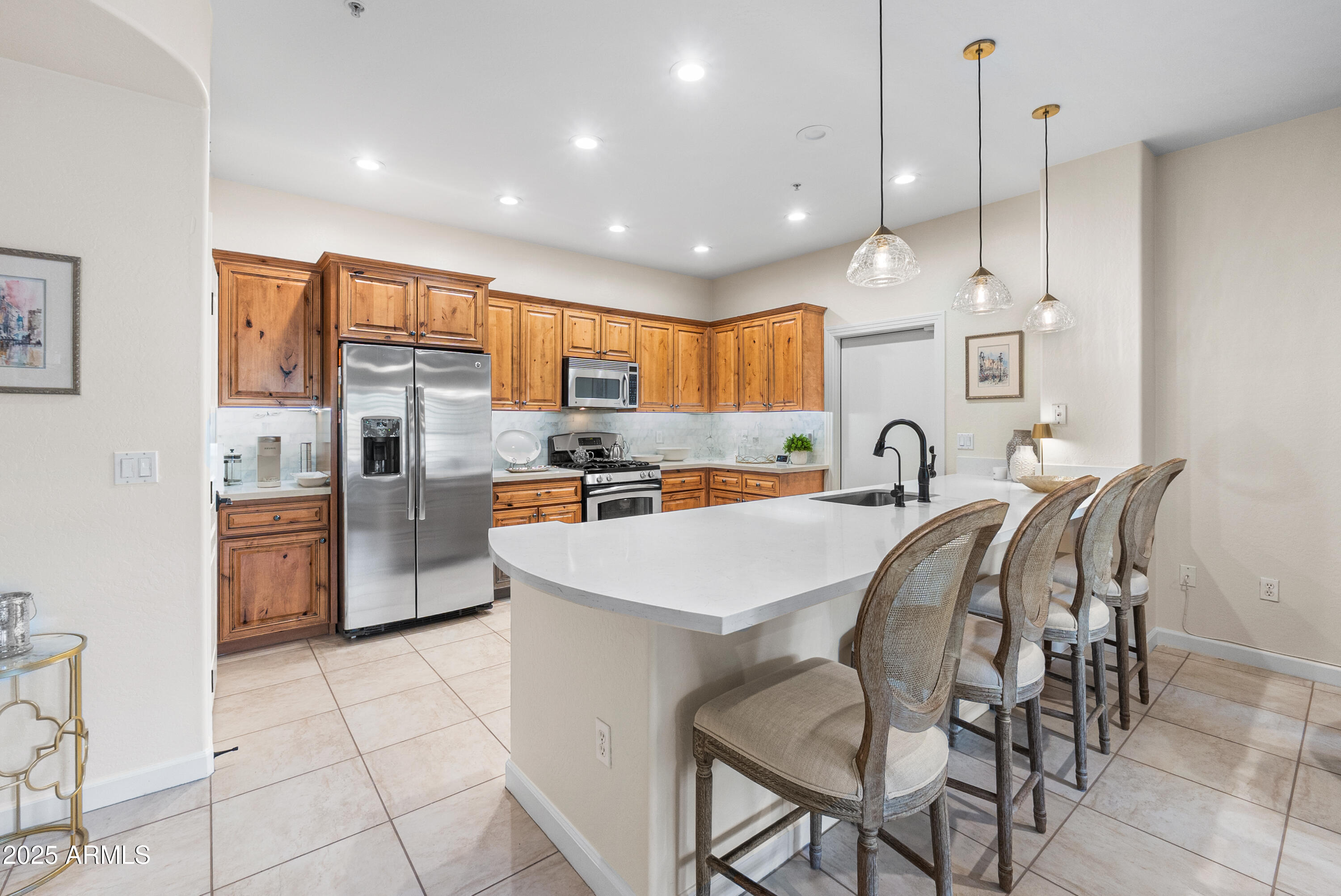 a kitchen with stainless steel appliances kitchen island granite countertop a stove a refrigerator a oven a sink with a dining table and chairs