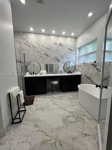 a bathroom with a tub a double vanity sink and a mirror