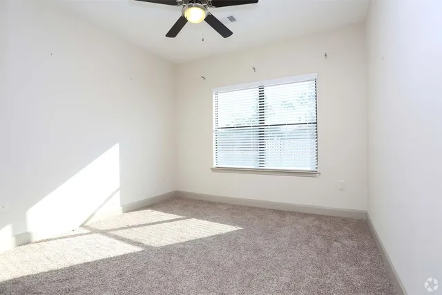 an empty room with a chandelier fan and windows