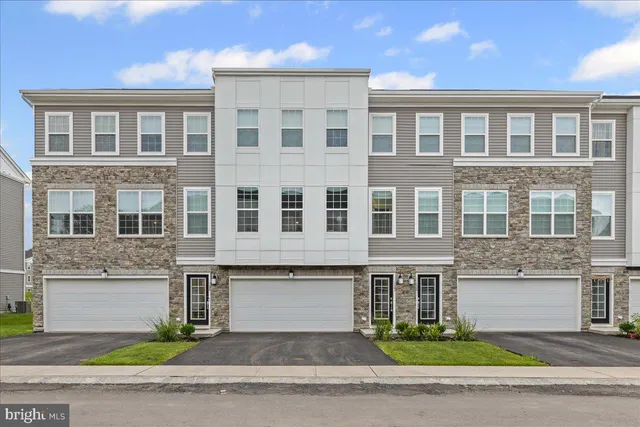 a front view of a building with garage and parking