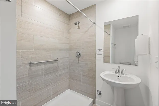 a bathroom with a sink shower and a mirror