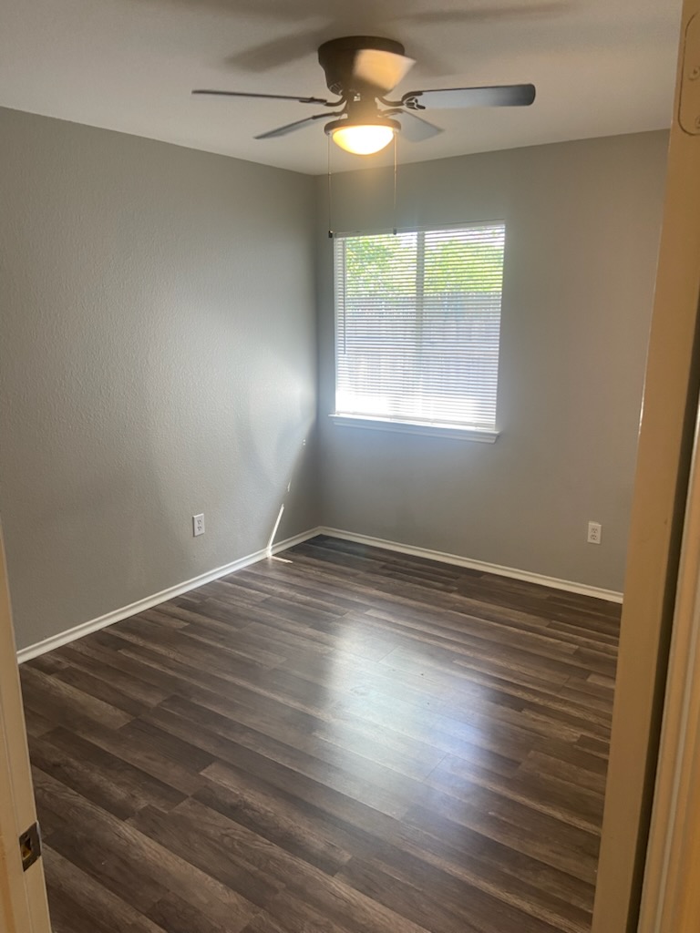 17616 Tobermory Drive Pflugerville, TX 78660 - Photo 10 of 14 A well-lit bedroom with rich wood flooring and a modern ceiling fan.