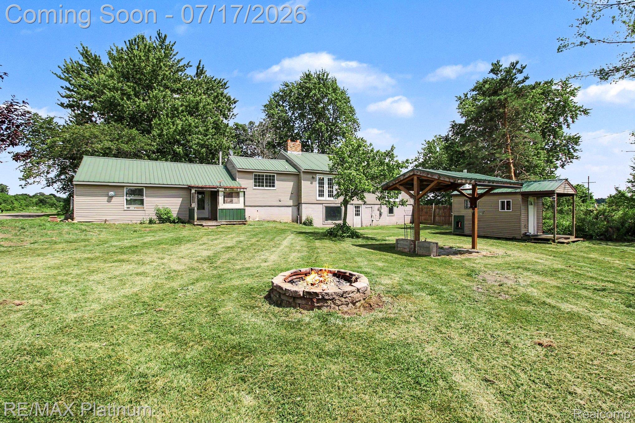 4205 Musson Road Howell, MI 48855 - Photo 3 of 23 Spacious backyard featuring a stone fire pit, detached shed, and a covered outdoor structure