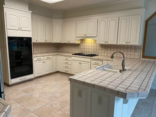 a kitchen with granite countertop a sink stainless steel appliances and cabinets