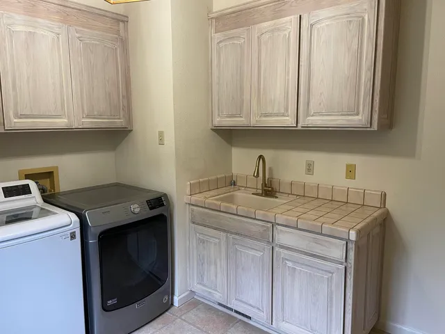 a utility room with granite countertop cabinets washer and dryer