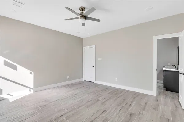 an empty room with wooden floor and ceiling fan