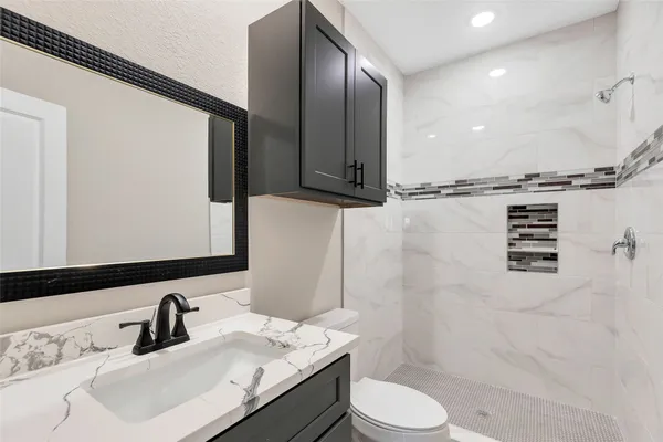 a bathroom with a granite countertop sink toilet a mirror and shower