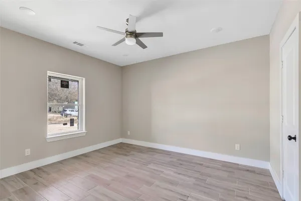 a view of empty room with wooden floor and fan