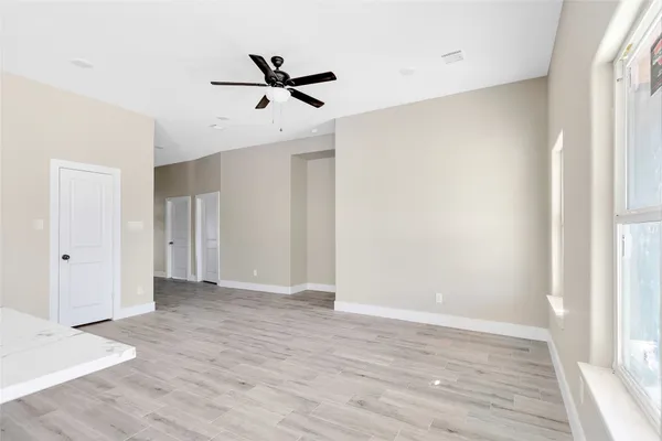a view of empty room with wooden floor and fan