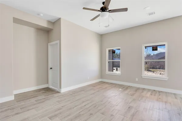 a view of an empty room with a window and wooden floor