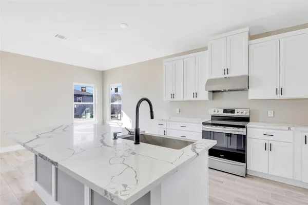a kitchen with a sink a stove and cabinets