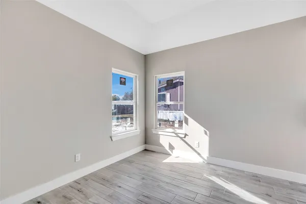 a view of an empty room with a window and wooden floor