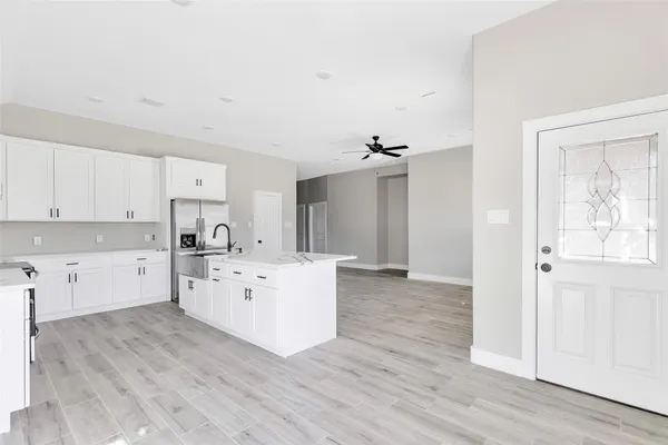 a large white kitchen with white cabinets and wooden floor