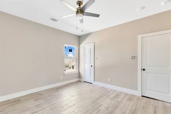 an empty room with wooden floor chandelier fan and windows
