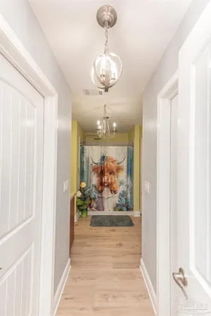 a view of a hallway with wooden floor and a chandelier