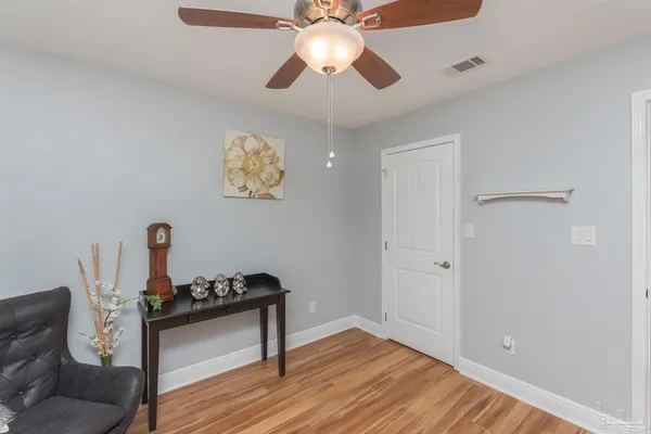 a view of a hallway to a livingroom with wooden floor and chandelier