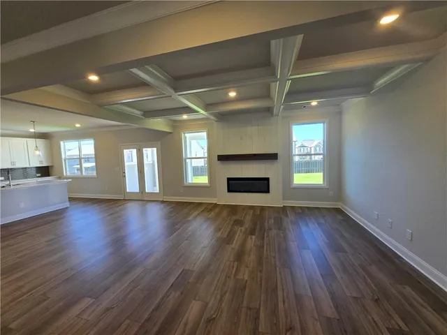 an empty room with wooden floor fireplace and windows