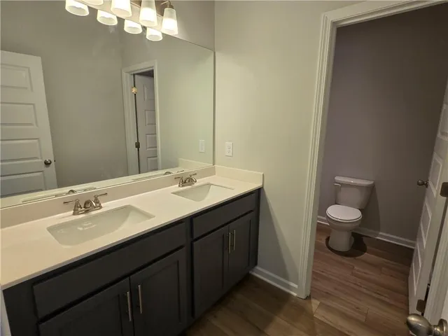 a bathroom with a granite countertop sink a toilet and a mirror