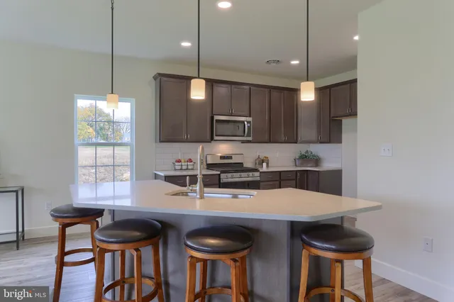 a kitchen with granite countertop a table chairs stove and refrigerator