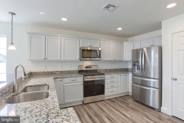 a kitchen with granite countertop a refrigerator stove and sink