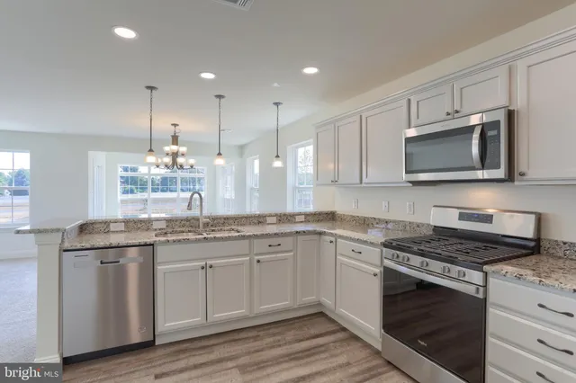 a kitchen with stainless steel appliances granite countertop wooden cabinets and a stove a oven with wooden floor