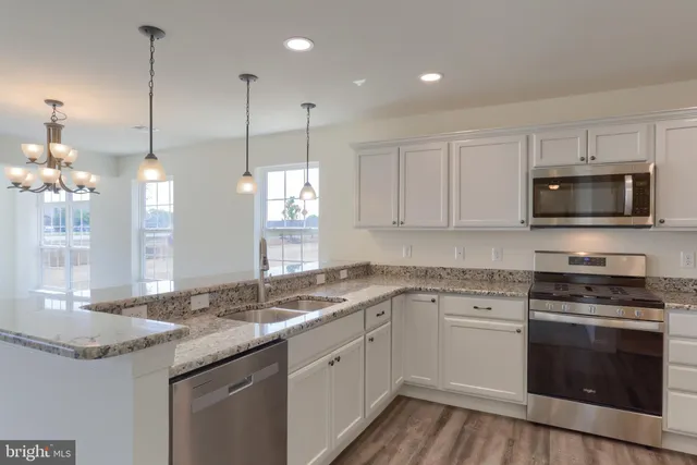 a kitchen with stainless steel appliances granite countertop a sink a stove and a wooden floor
